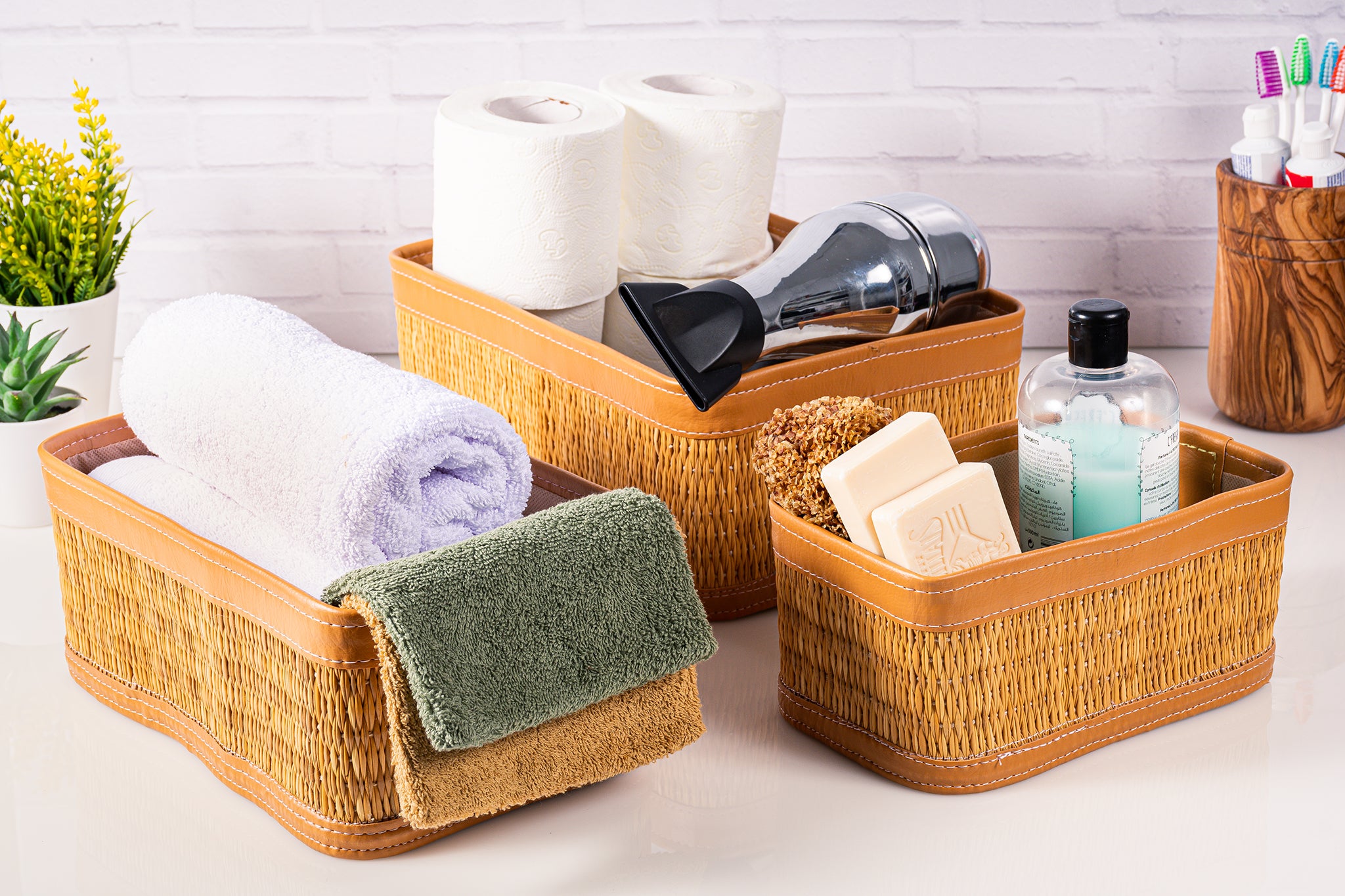 Set of 3 handmade natural fiber darido storage boxes with brown leather trim, filled with toiletries and towels. - Set of 3 Handmade Natural Fiber Storage Boxes with Colored Leather Trim