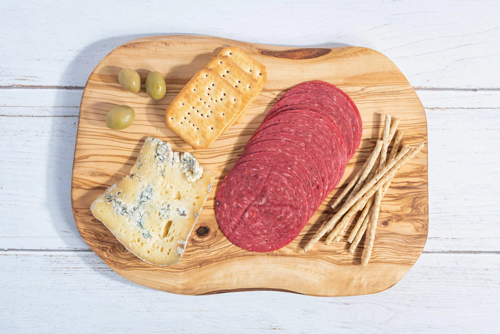 Darido handmade olive wood cutting board with cheese, salami, breadsticks, and olives on white surface. - Handmade Olive Wood Cutting Board – Reversible, Rustic & Food-Safe | 12x7" (30x18cm)