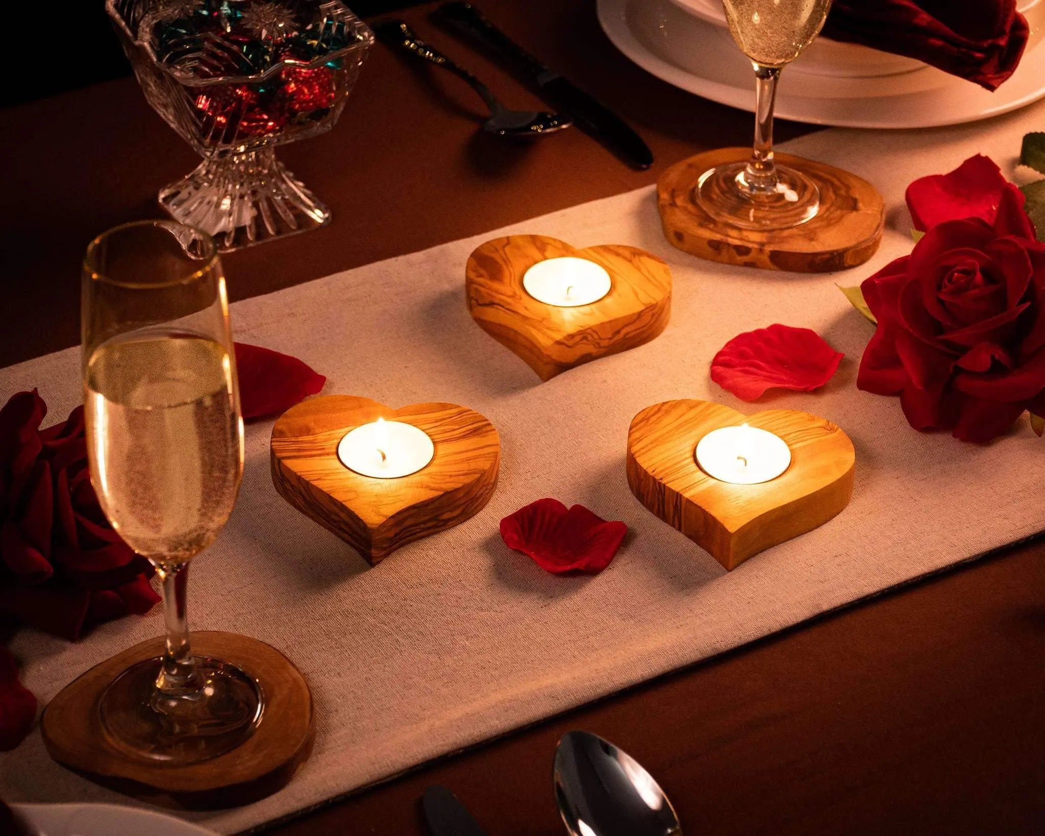 Heart-shaped olive wood tealight holders with lit candles on a table, branded darido. - Olive Wood Tealight Holder - Heart Shape - 10x10x2 cm