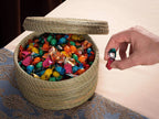 Round halfa darido basket with lid, filled with colorful wrapped candies on blue patterned surface. - Round Halfa Basket