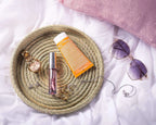 Round Darido Halfa basket with natural woven texture holding perfume, lotion, and jewelry on white fabric background. - Round Halfa Basket