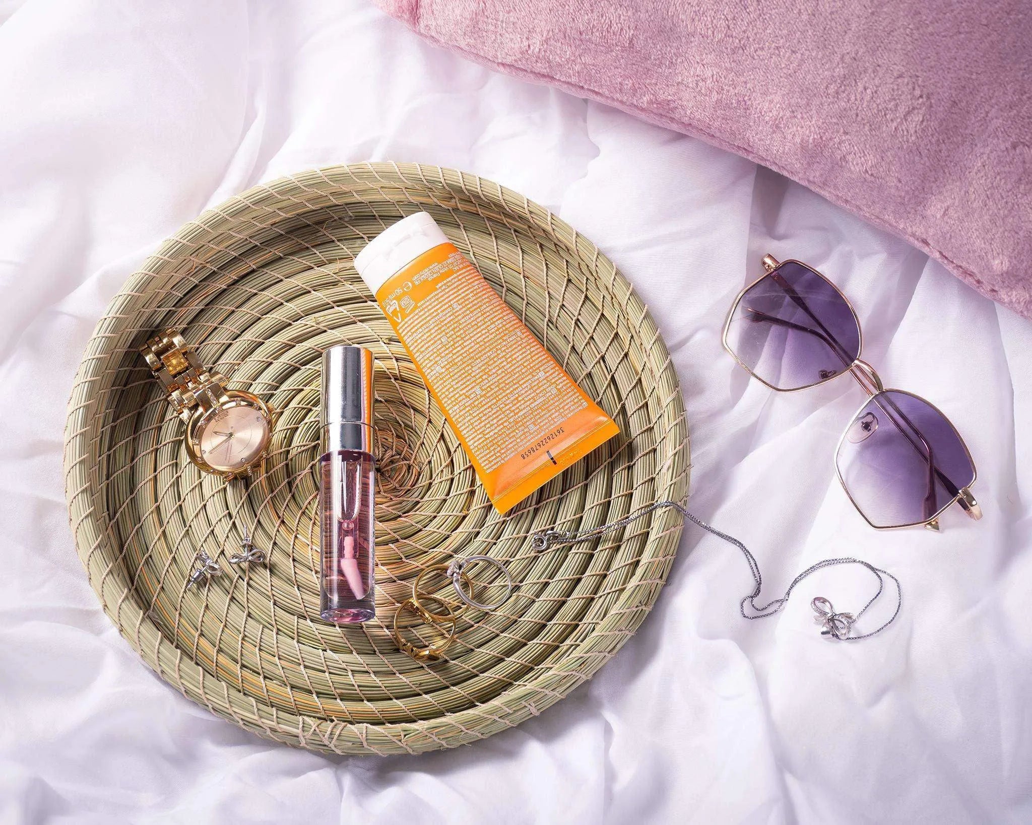 Round Darido Halfa basket with natural woven texture holding perfume, lotion, and jewelry on white fabric background. - Round Halfa Basket