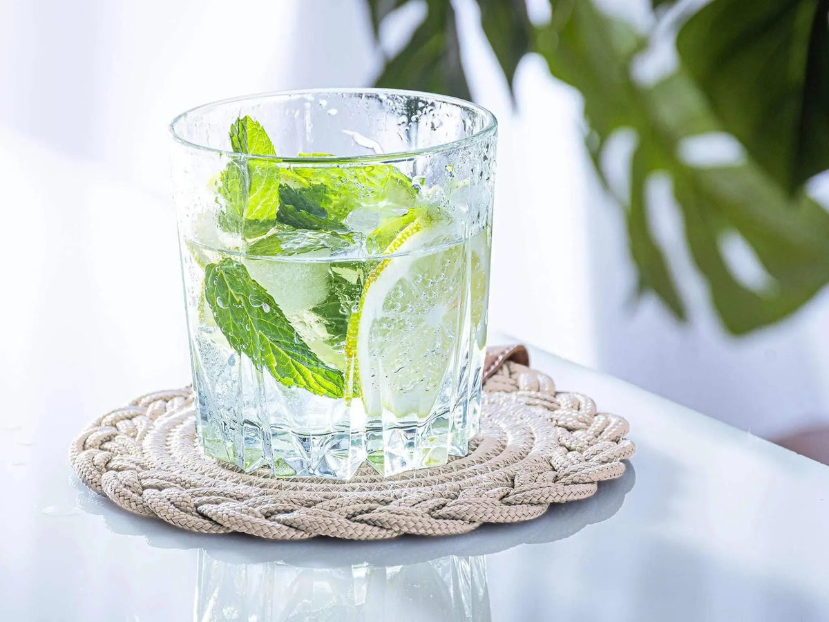 Set of 2 beige darido cotton coasters with braided design under clear glass of lime-infused water. - Set of 2 Beige Coasters - 15cm