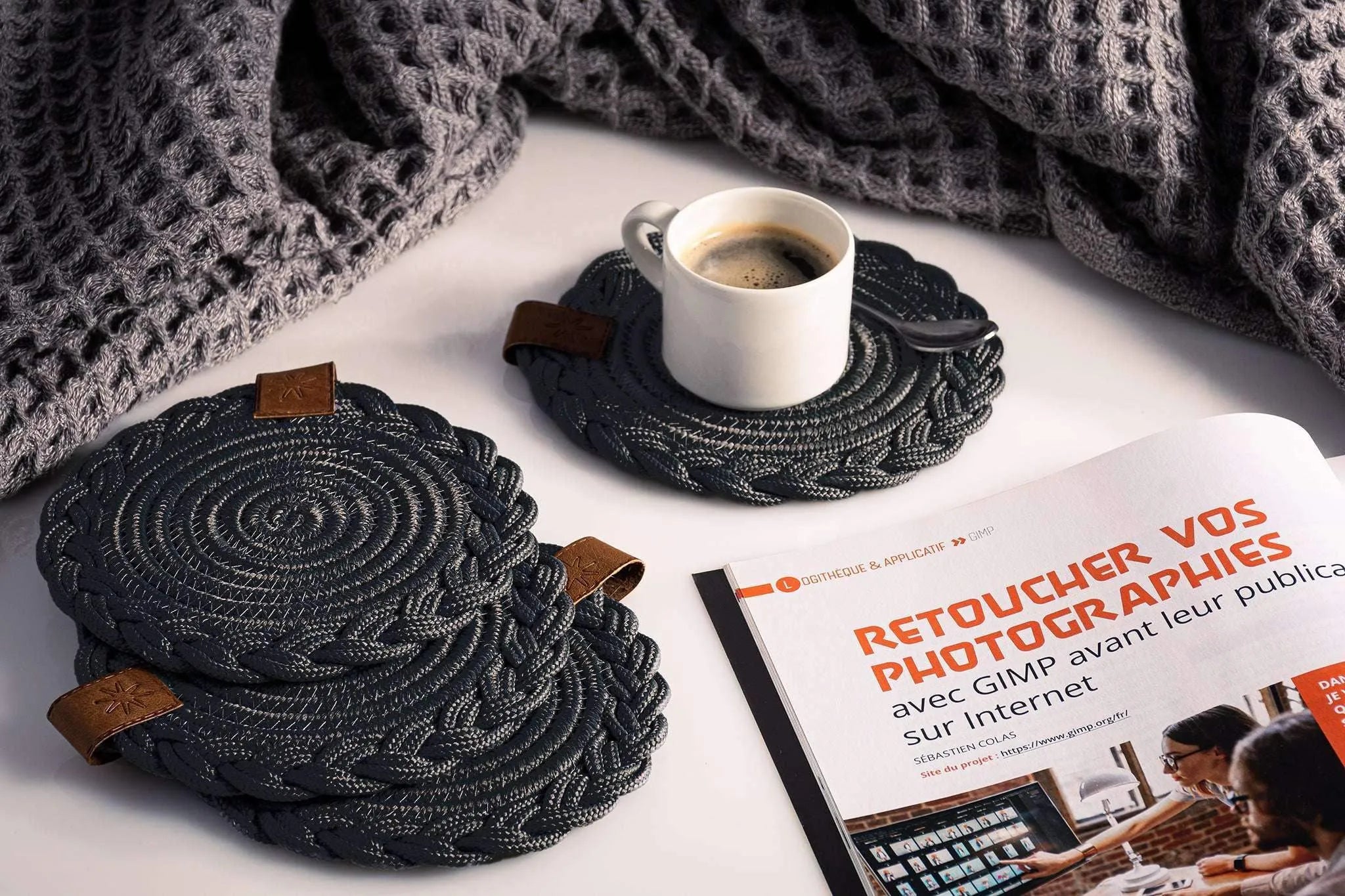 Set of 2 black Darido cotton coasters with textured spiral design on a tabletop. - Set of 2 Black Coasters- 15cm