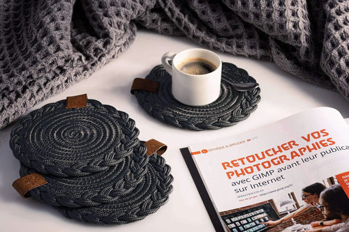 Set of 2 black Darido cotton coasters with textured spiral design on a tabletop. - Set of 2 Black Coasters- 15cm