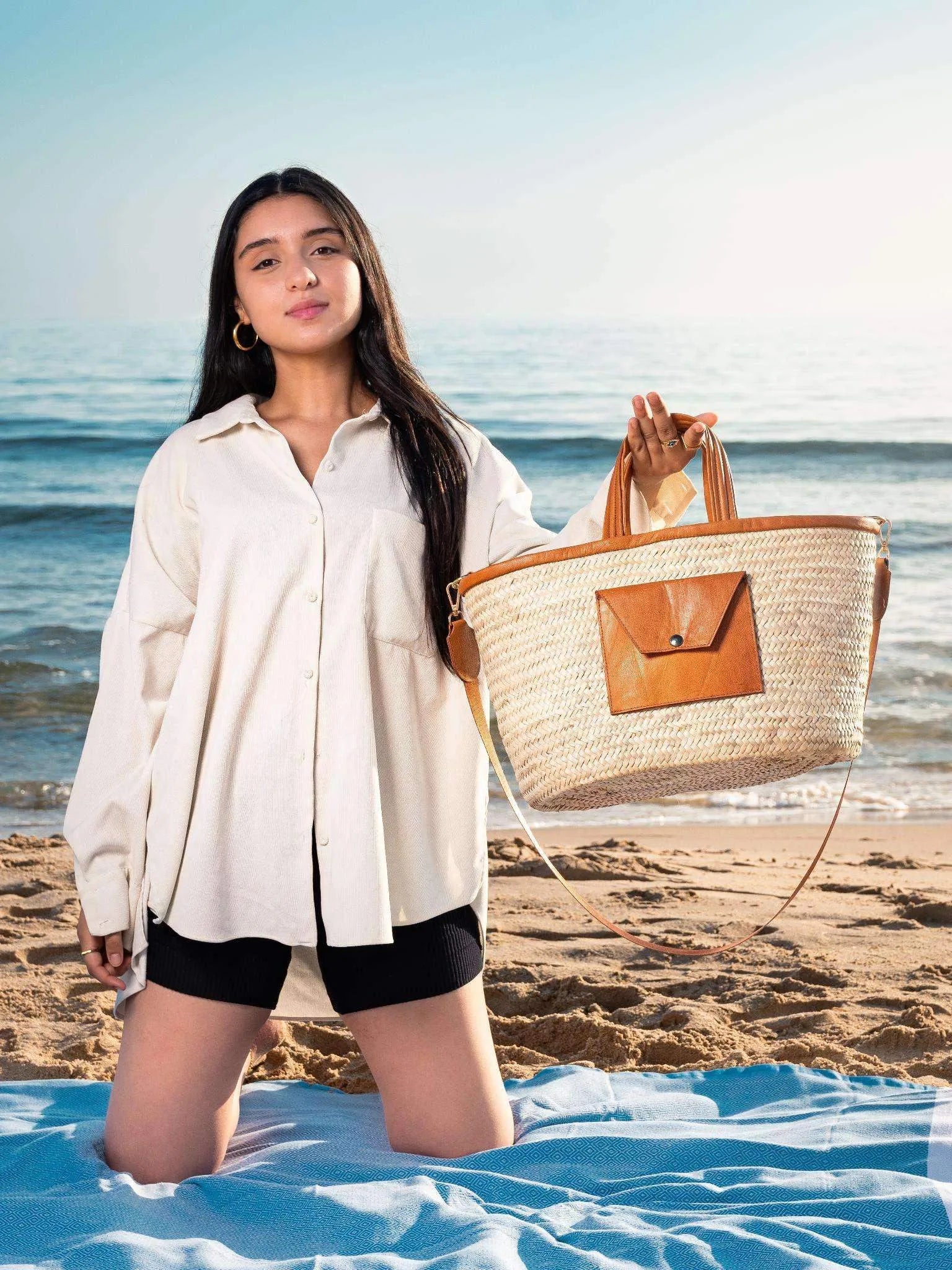 Darido woven shopping bag with tan leather pocket, held by woman on beach. - Shopping Bag Saaf with Leather Pocket M